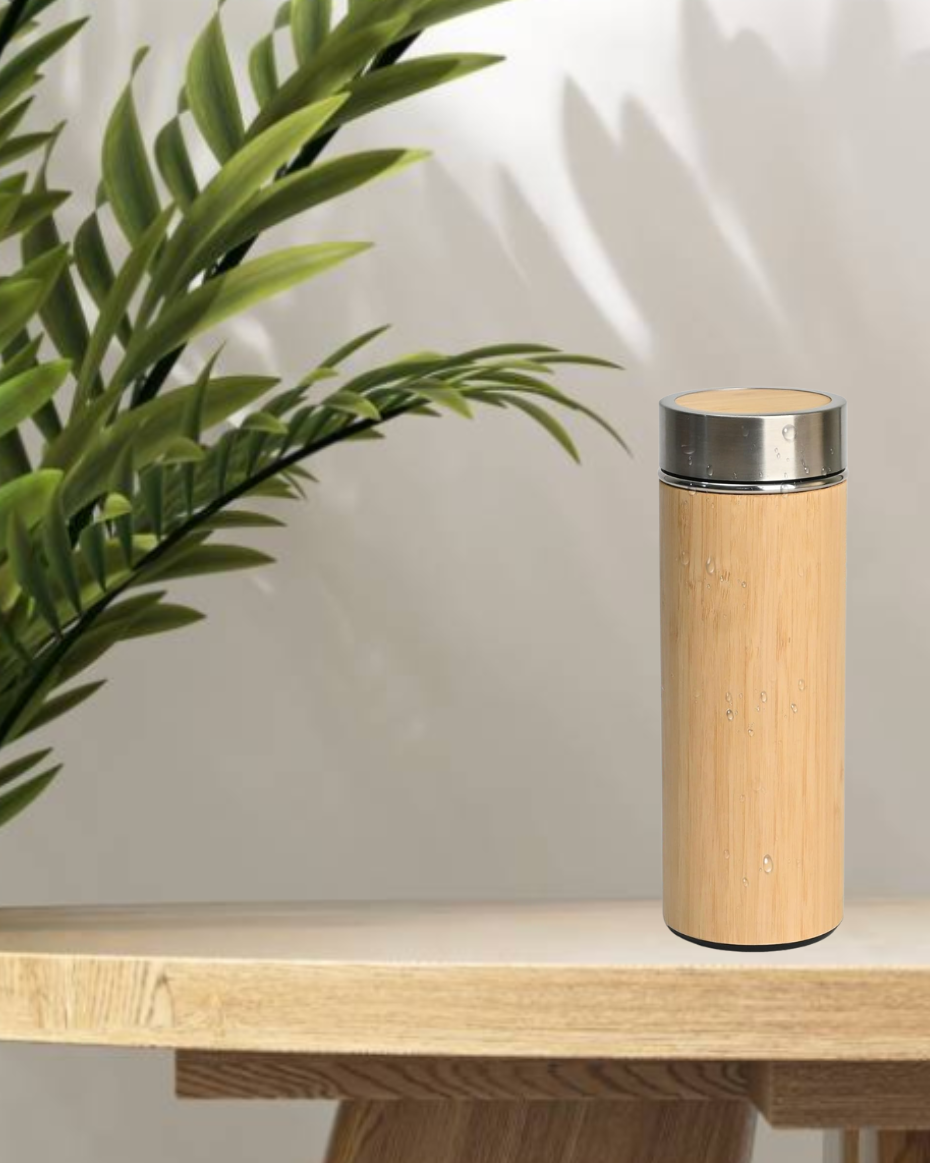 Bamboo water bottle on a wooden surface with a plant in the background