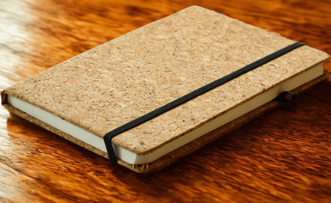 Cork notebook with a black strap on a wooden surface