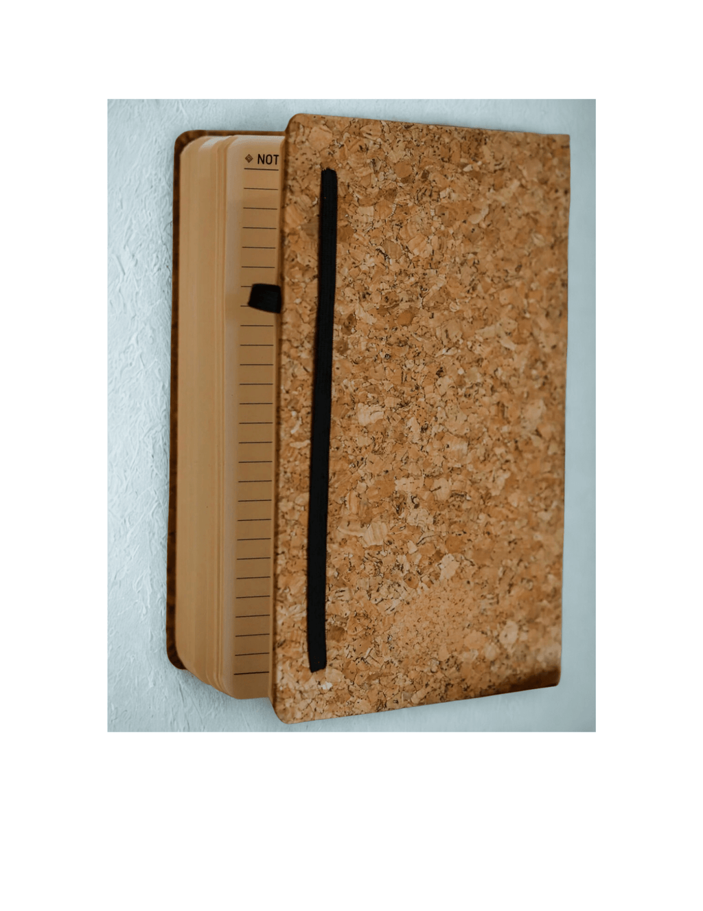 Notebook with cork cover and black strap on a light blue background