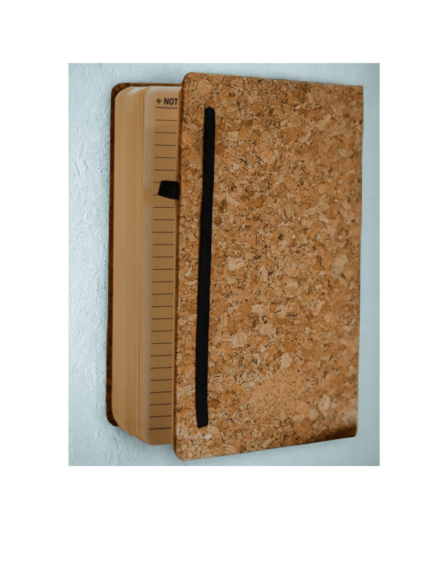 Notebook with cork cover and black strap on a light blue background