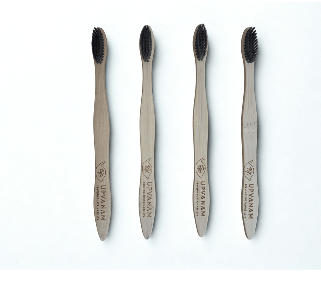 Four bamboo toothbrushes with black bristles on a white background