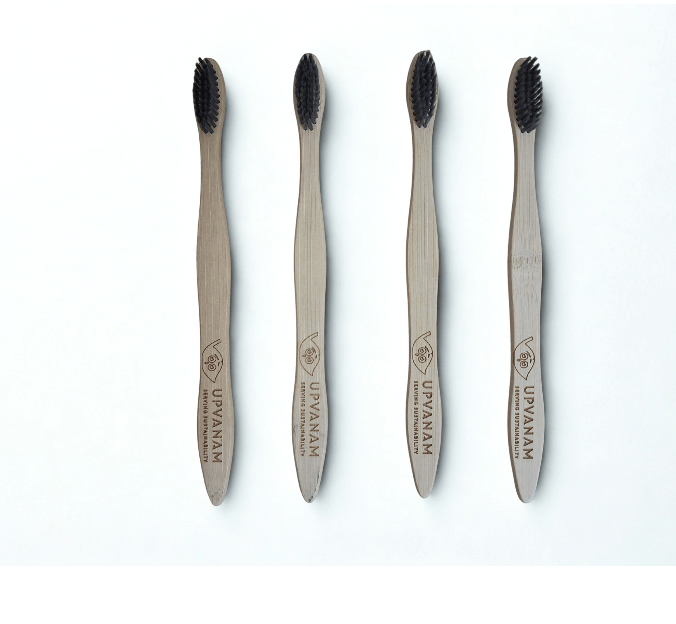 Four bamboo toothbrushes with black bristles on a white background