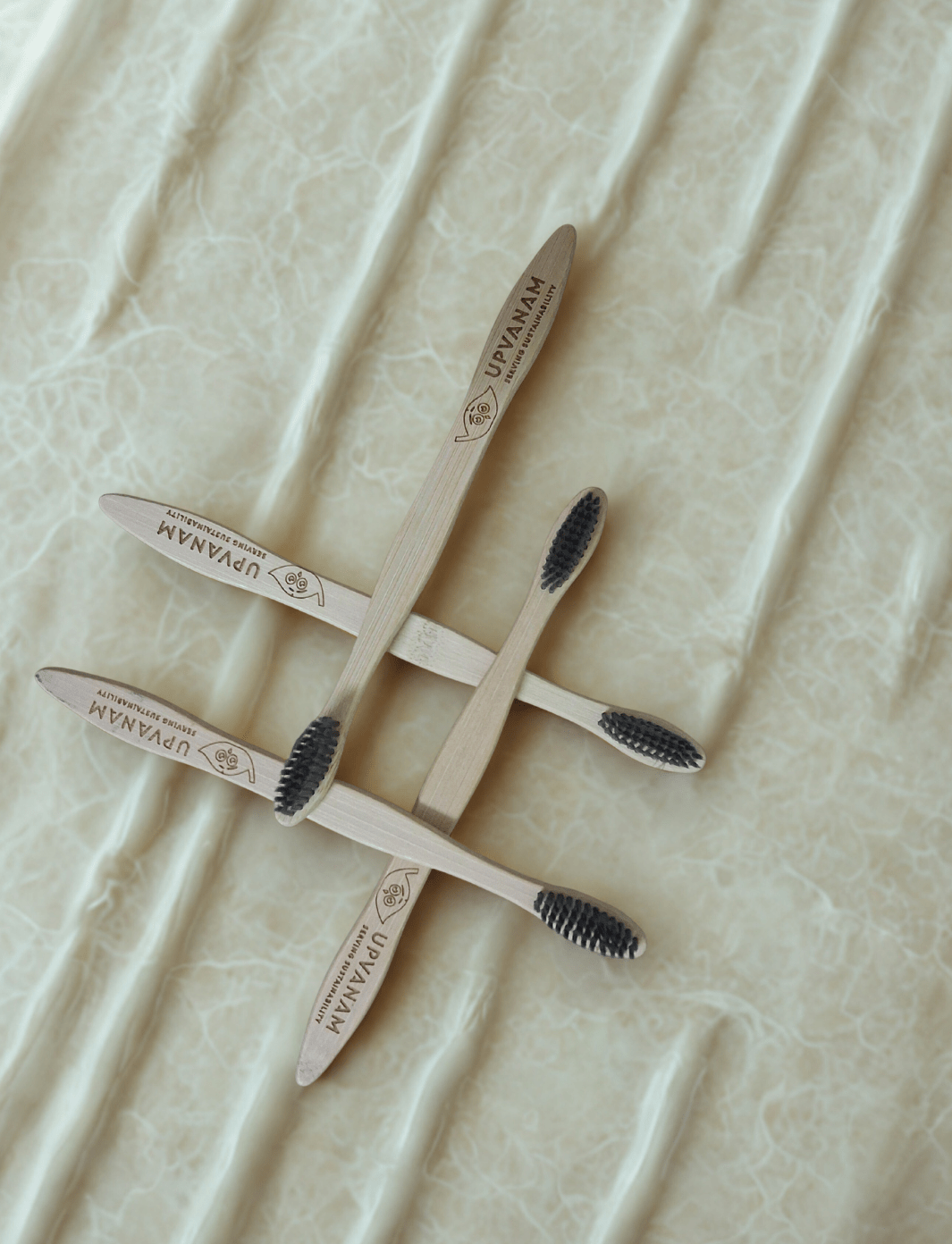 Set of wooden toothbrushes with black bristles on a textured beige surface