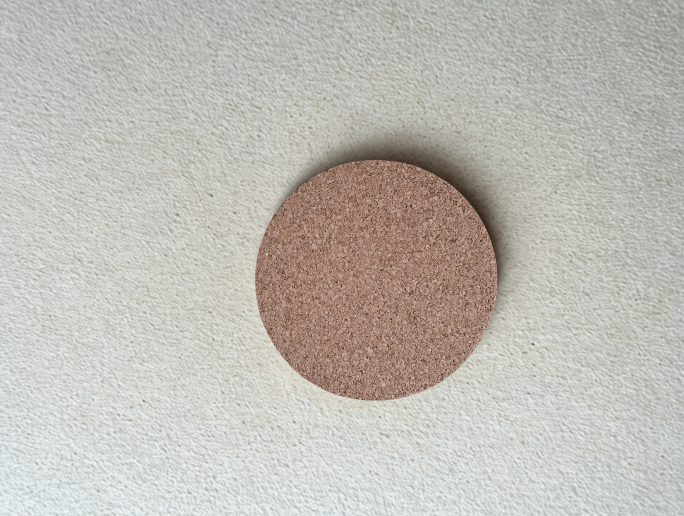 Round wood cork coaster on a textured gray surface