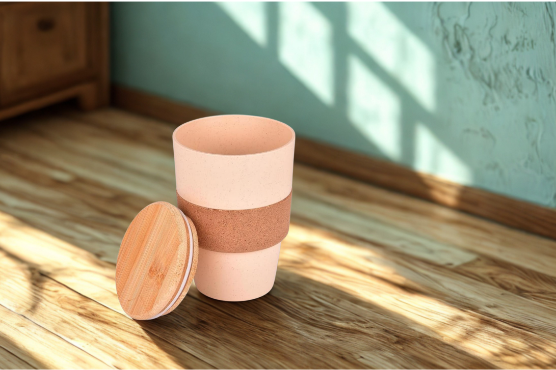 wheat straw coffee mug with a bamboo lid on a wooden floor.