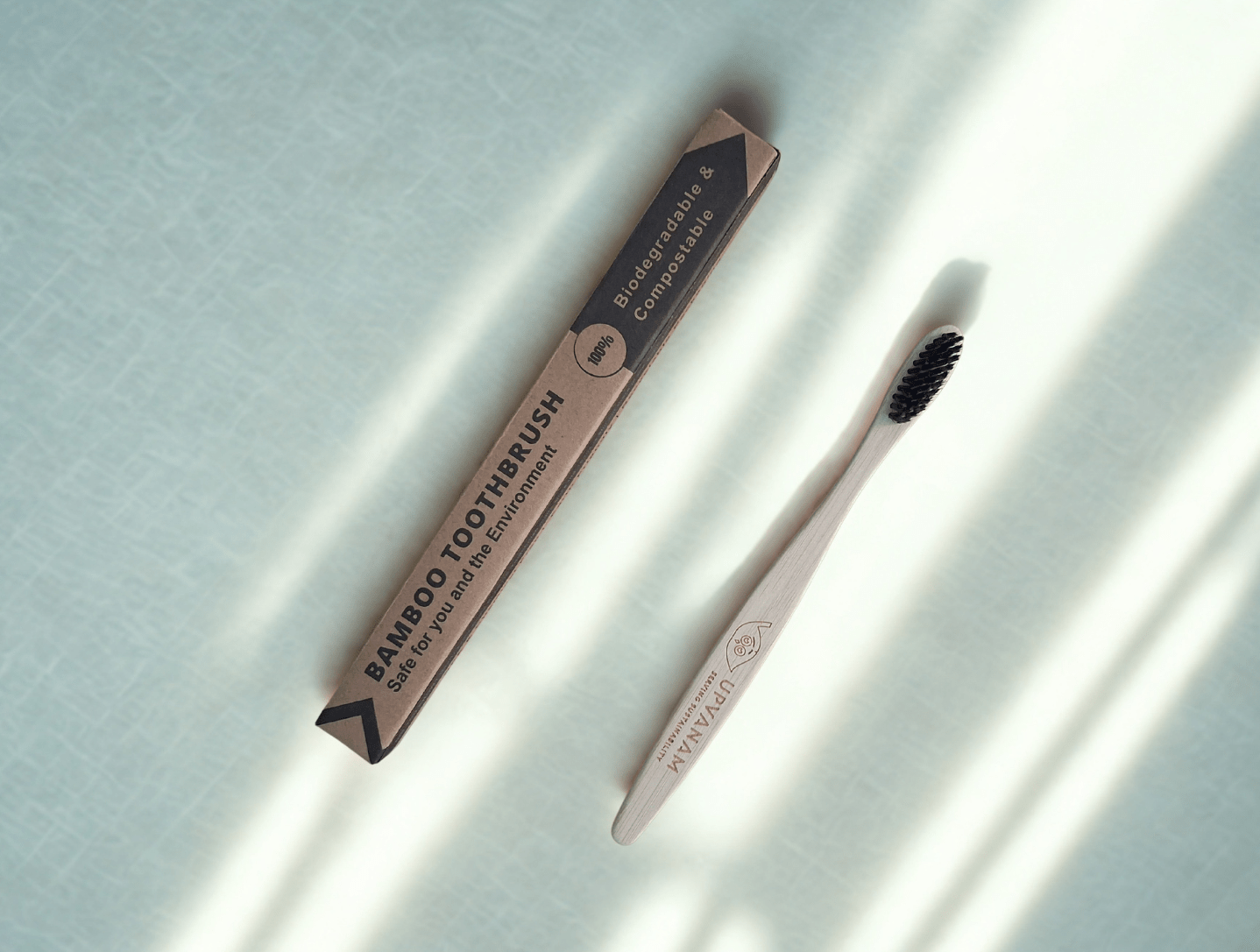 Bamboo toothbrush and eco friendly packaging on a light background