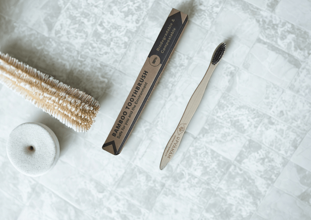 Bamboo toothbrush and brush head on a textured white surface